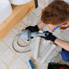 Kiedy hydraulik na budowie montuje syfon pod umywalką, używając narzędzi i nowych rur.