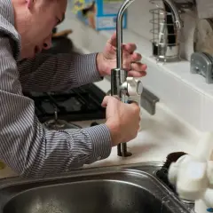 Mężczyzna naprawia kran. Zastanawiasz się, ile zarabia hydraulik w Niemczech?
