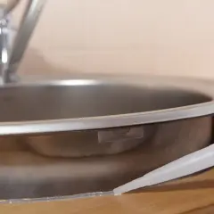 Aplikacja silikonu sanitarnego wokół zlewu. Zastanawiasz się, jak długo schnie silikon sanitarny? Czas schnięcia zależy od wielu czynników.