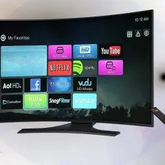 Zakrzywiony telewizor z ikonami aplikacji, pilot w ręku. Zastanawiasz się, ile prądu pobiera telewizor?