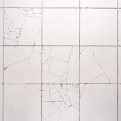 Pęknięte białe płytki na ścianie, z widocznymi liniami pęknięć. Dowiedz się, jak naprawić pękniętą płytkę, aby przywrócić jej estetykę.