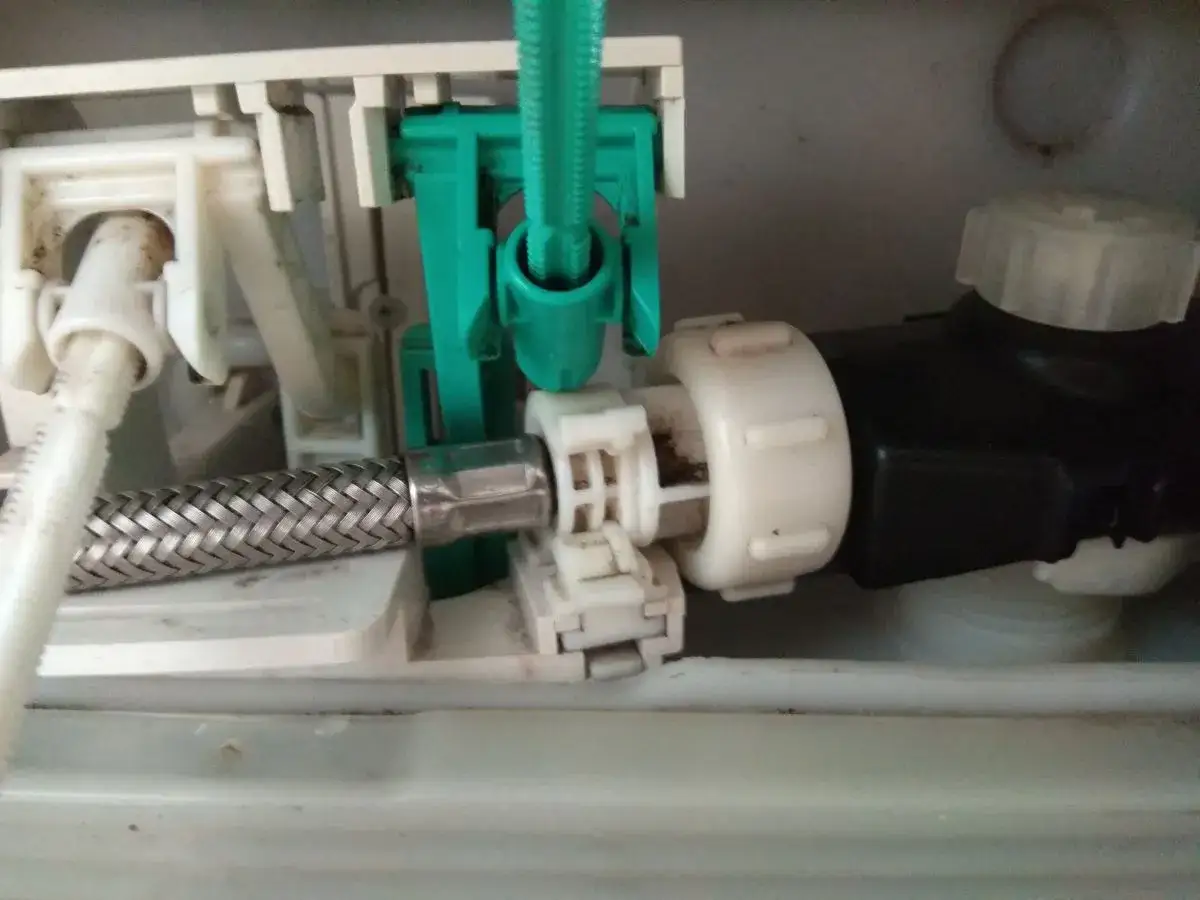 Mechanizm spłuczki Geberit, gdzie widać metalowy wężyk i zielony element. Problem: geberit nie pobiera wody.